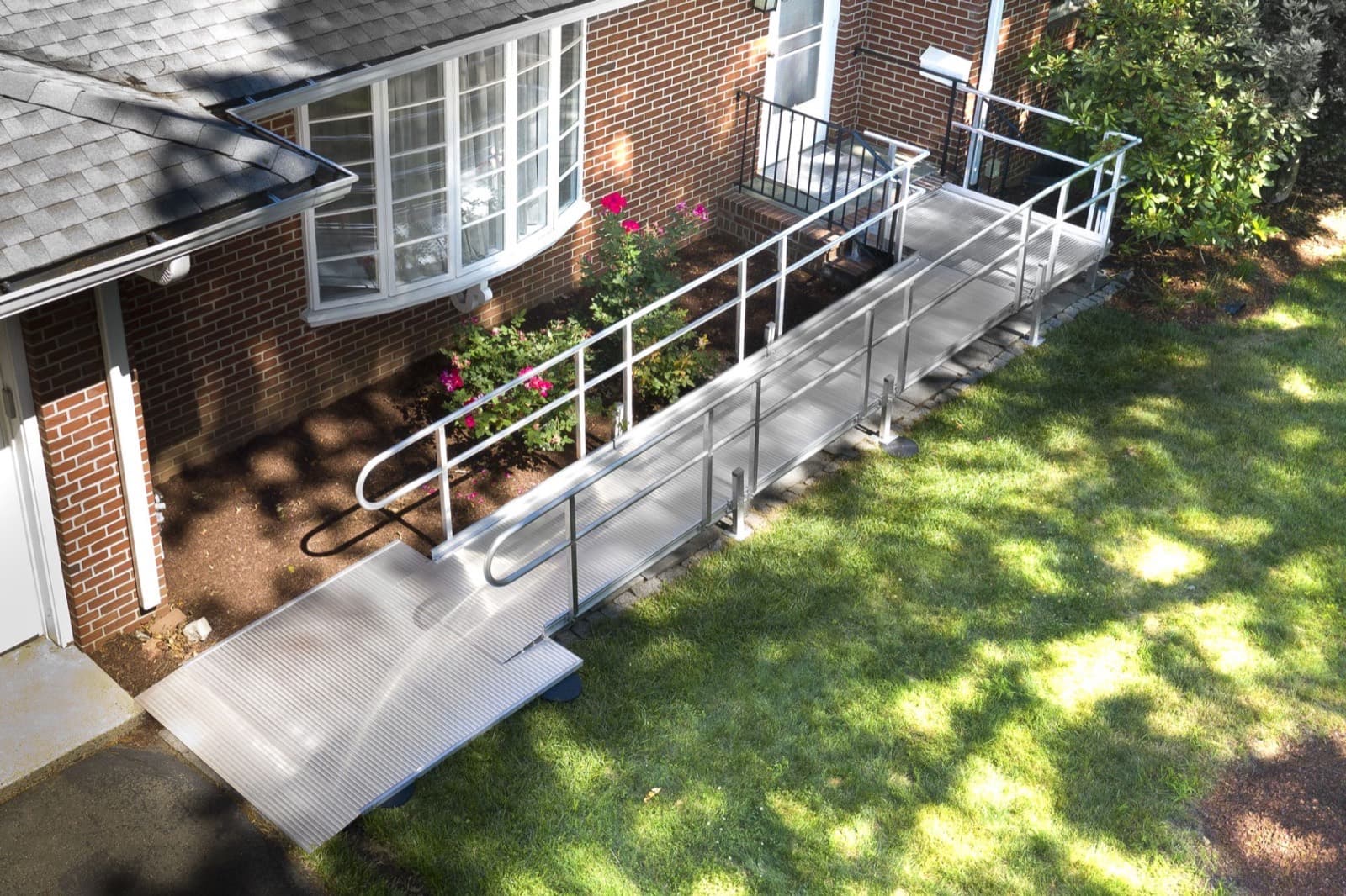 Completed aluminum wheelchair ramp with handrails at a residential entry
