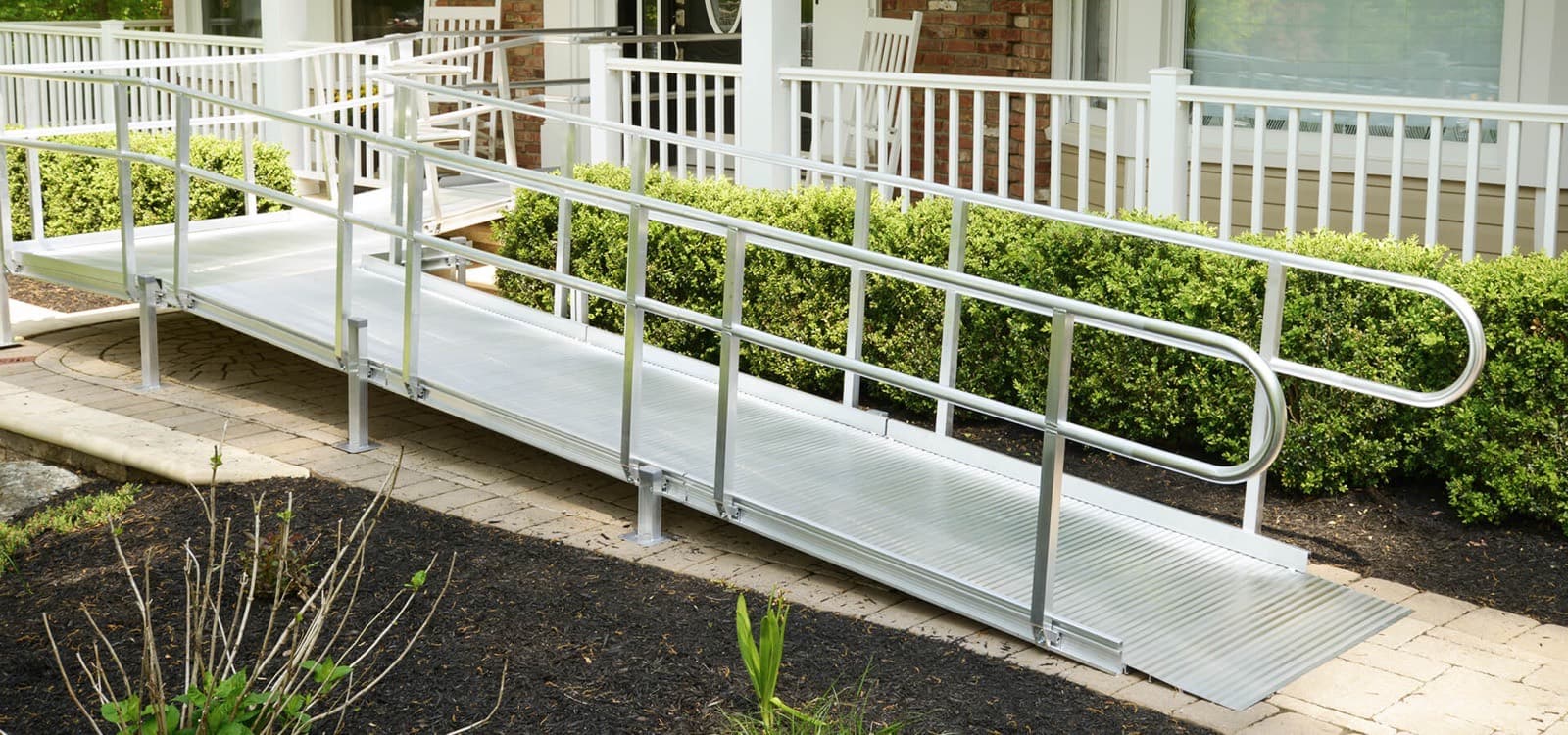Aluminum wheelchair ramp running alongside a front porch