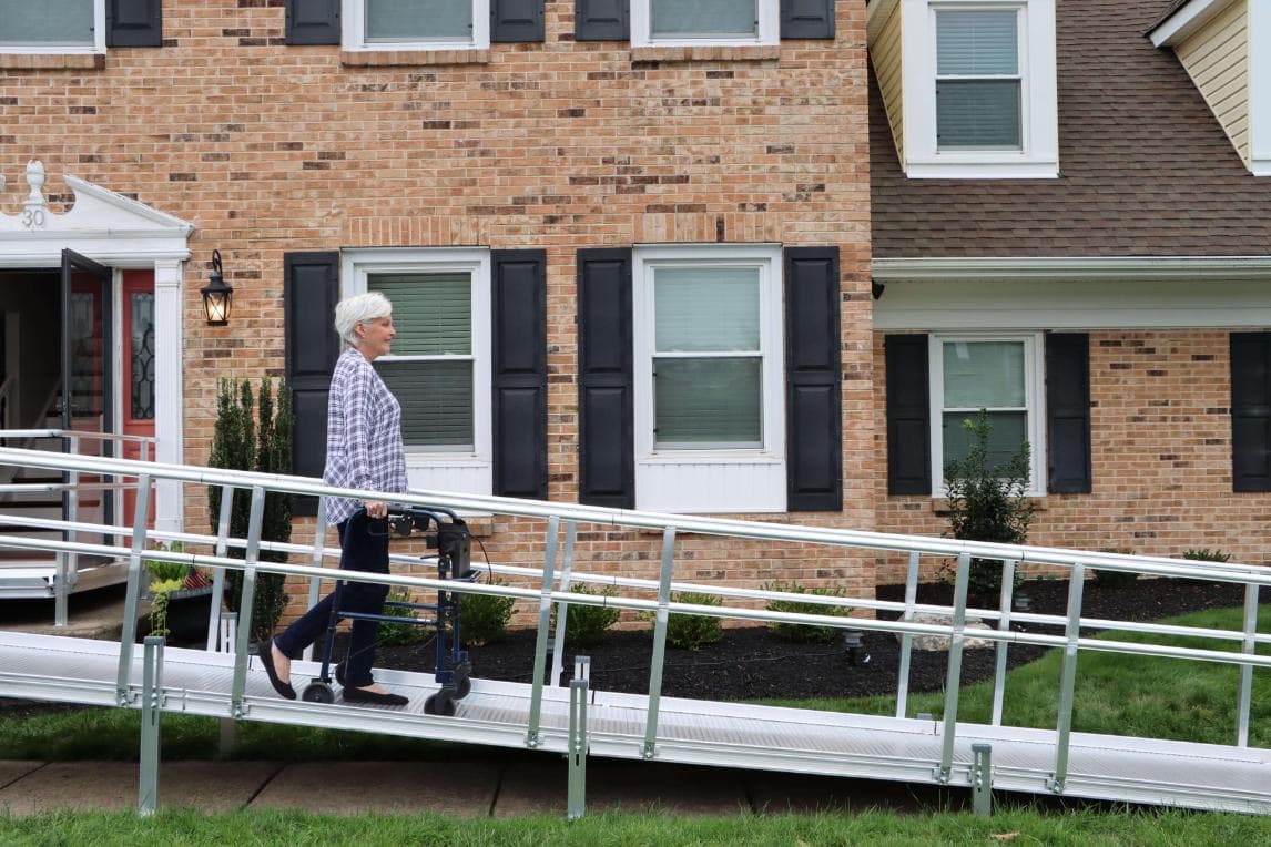 A woman using a walker crossing a residential ramp to her front door